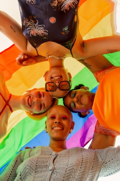 Four people under a pride flag.