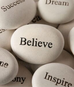 Stones with affirmative words: believe, inspire, dream, succeed.