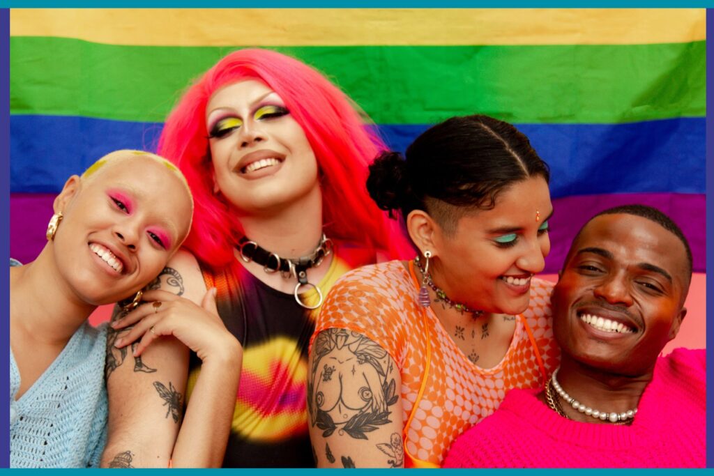 People standing in front of a queer pride flag.