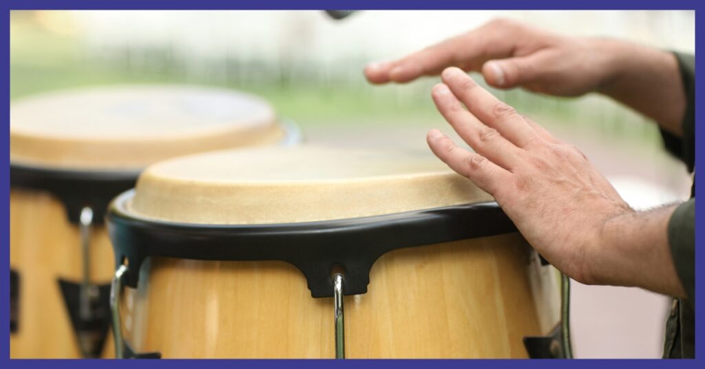 A picture of 2 bongo style drums and a persons hands.