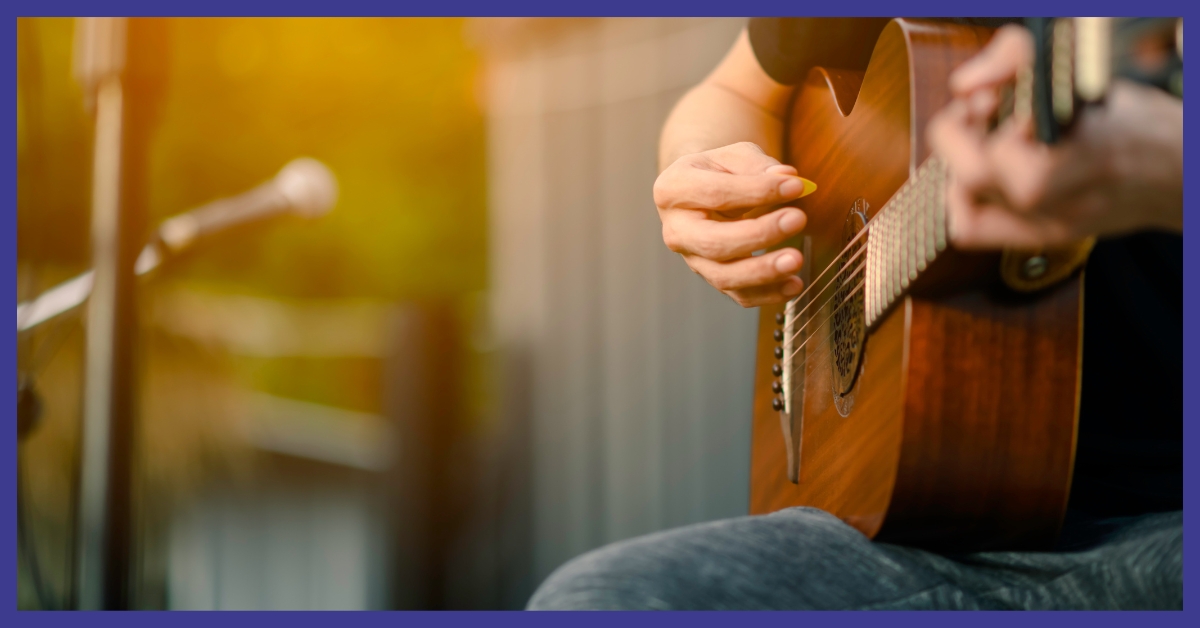 A person sitting outside playing a guitar.