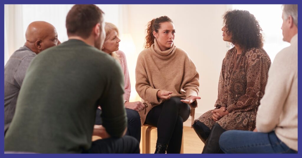 Men and women sitting in a circle talking.